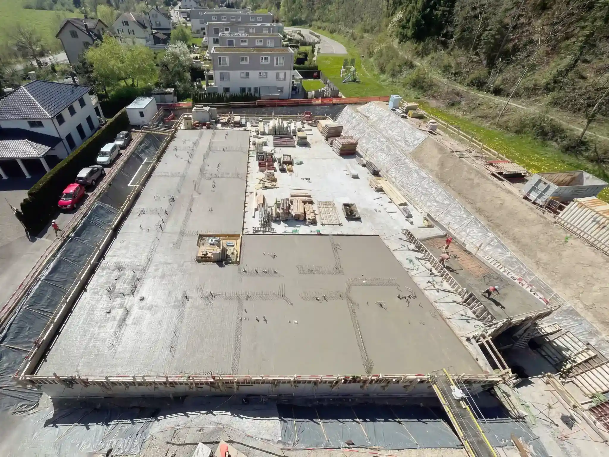 Luftaufnahme einer Baustelle in Hanglage mit betonierter Bodenplatte