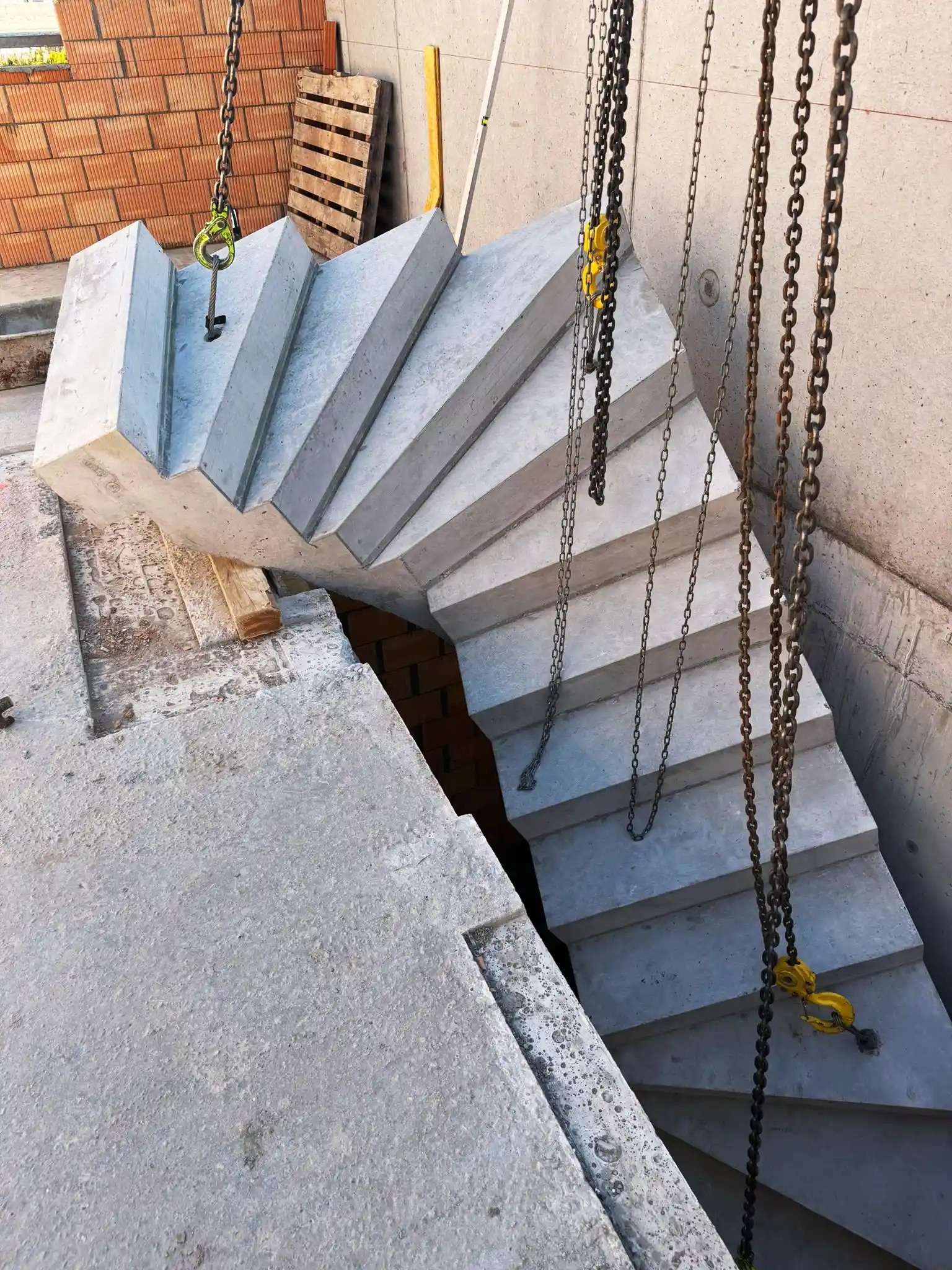 Vorgefertigte Betontreppe (Fertigteiltreppe), die gerade mit einem Kran eingehoben wird.